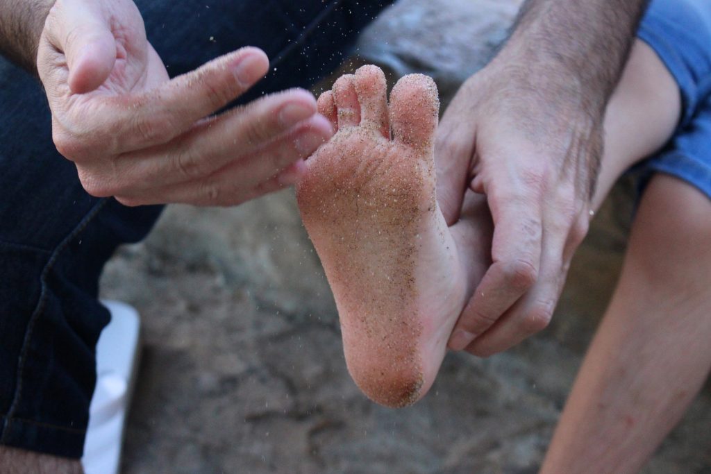 man cleaning boys sandy feet