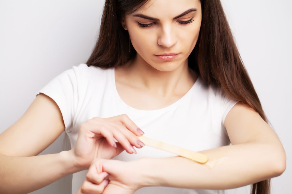 young woman doing hair removal home hands area